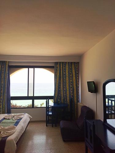 a hotel room with a bed and a window with the ocean at Residence Boujaafar in Sousse