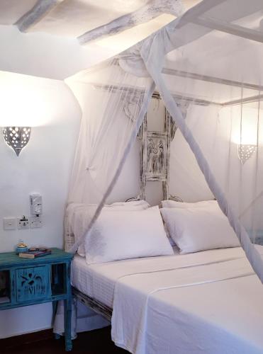 a bedroom with a white bed and a blue table at Diwani Cottage in Malindi