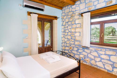a bedroom with a bed and a stone wall at Villa Ostria in Georgioupolis