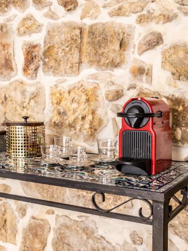a red toaster sitting on a table in front of a stone wall at Flora Valley Boutique Hotel in Jerusalem