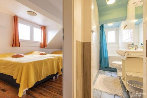 a bedroom with a bed and a bathroom with a sink at Les Bastinettes in Stoumont
