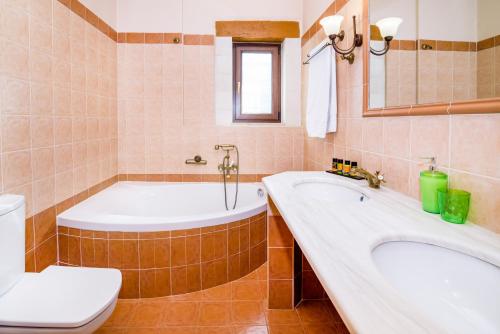 a bathroom with a tub and a toilet and a sink at Villa Ostria in Georgioupolis