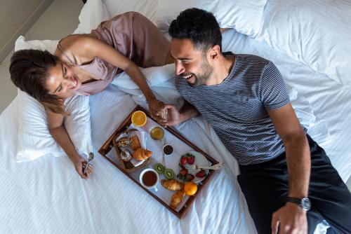 a man and woman laying on a bed with a tray of food at Grand Ocean El Sokhna in Ain Sokhna
