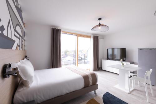 a hotel room with a bed and a desk and a television at Aparthotel Adagio Bâle Mulhouse Aeroport in Blotzheim