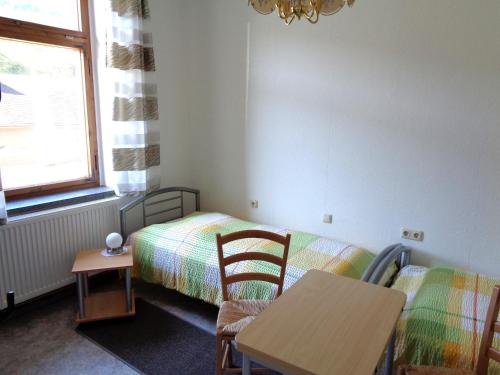 1 dormitorio con 1 cama, mesa y sillas en Pension Bahnmeister, en Probstzella