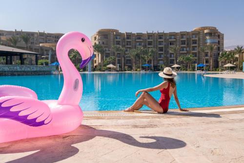 a woman sitting next to a pink swan in a pool at Grand Ocean El Sokhna in Ain Sokhna