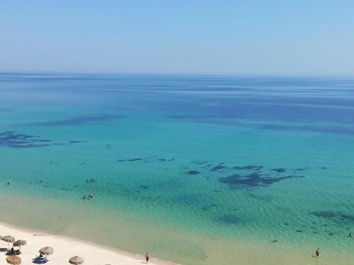 una playa con sombrillas y gente en el agua en Residence Boujaafar, en Sousse