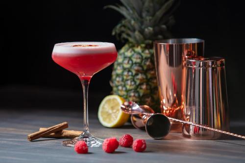 a drink in a martini glass next to a pineapple at Hotel de Leijhof Oisterwijk in Oisterwijk