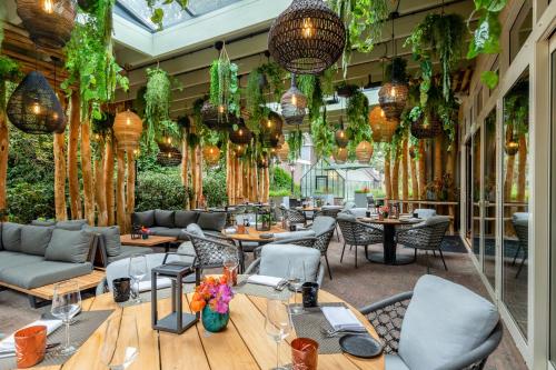 restauracja ze stołami, krzesłami i roślinami w obiekcie Hotel de Leijhof Oisterwijk w mieście Oisterwijk