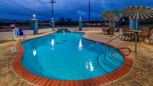 a pool at night with a table and chairs at SureStay Plus Hotel by Best Western Alvin in Alvin