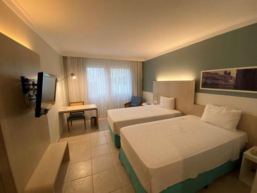 a hotel room with a bed and a desk at Mercure Salvador Rio Vermelho in Salvador