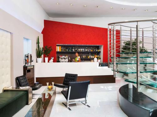 a bar with a red wall and black chairs at Ibis Styles Milano Centro in Milan