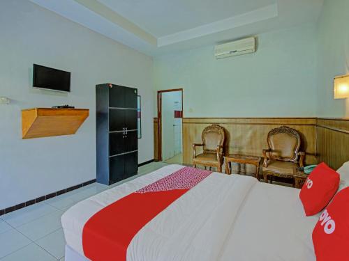 1 dormitorio con 1 cama grande y 2 sillas en OYO 3934 Hotel Istana, en Pekalongan