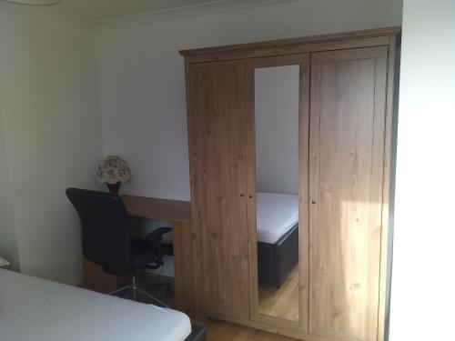 una camera da letto con armadio in legno e scrivania di Large double room or single room with shared bathroom ad Ash
