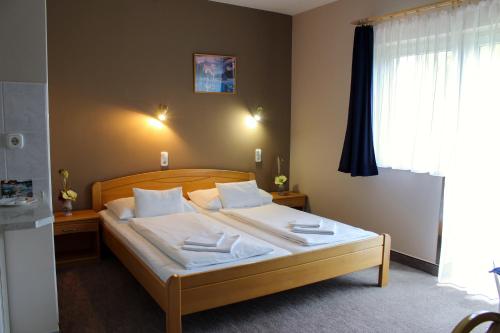 a bedroom with a bed with white sheets and pillows at Lídia Hotel in Harkány