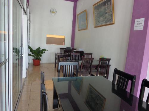 una sala da pranzo con tavoli, sedie e pareti viola di Hotel Musafir Inn a Padang