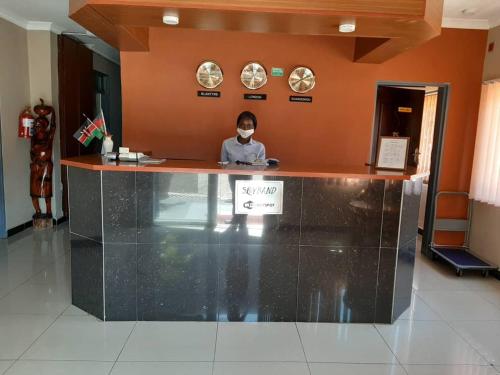 a person wearing a mask sitting at a counter in a lobby at Top Lodge in Blantyre in Blantyre