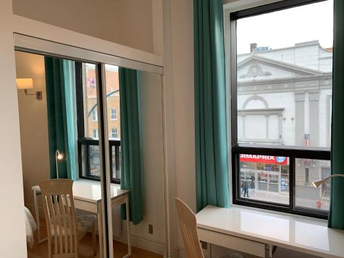 a room with a table and two windows with green curtains at Chambres EL MEDITERRANEO Rooms in Montréal