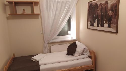 a small bedroom with a window and a bed with white sheets at Apartament na Kawiarach in Gniezno