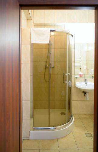 a bathroom with a glass shower with a sink at Gościniec Czarci Młyn in Będzin