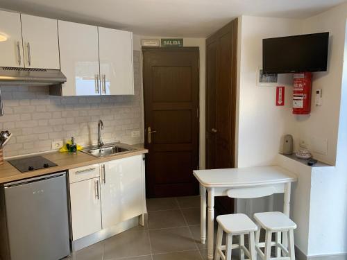 a kitchen with white cabinets and a sink and a table at Apartamentos Finca Wapa in Frontera