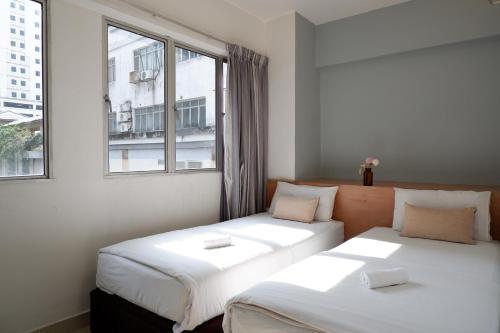 dwa łóżka w pokoju z oknem w obiekcie Indah Garden Hotel w mieście Ampang Resettlement