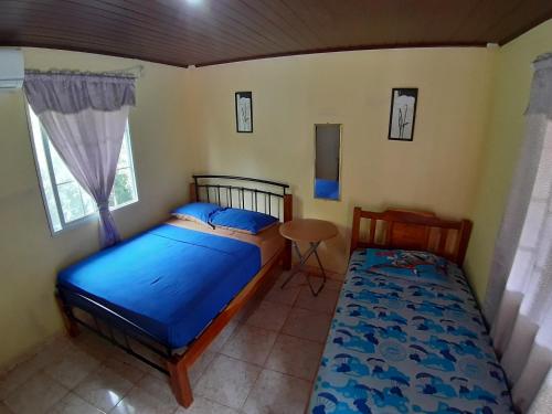 1 dormitorio con 2 camas, mesa y ventana en Oceans Hostal, en Santa Catalina