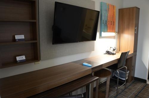 a hotel room with a desk with a television on the wall at MainStay Suites Bowling Green North in Bowling Green