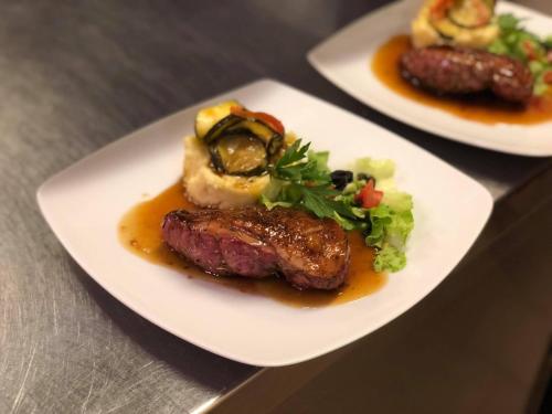 two plates of food with meat and vegetables on a table at Auberge du Renard'eau in Bèze