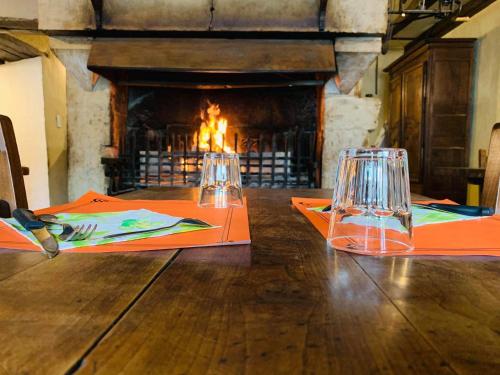 a wooden table with two glasses and a fireplace at Auberge du Renard'eau in Bèze