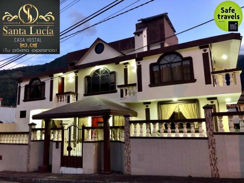 a large white house with a gate and a balcony at Hotel Casa Santa Lucía in Baños