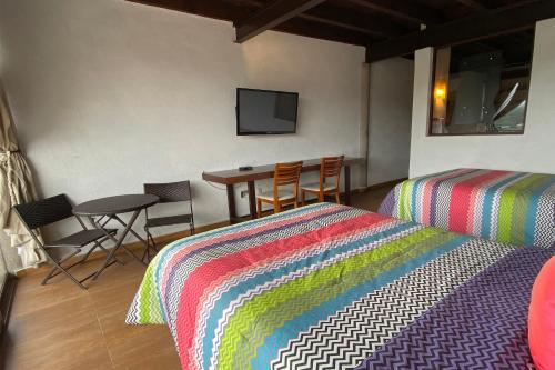 a bedroom with two beds and a table with chairs at Hotel Santa Rosa in Valle de Bravo