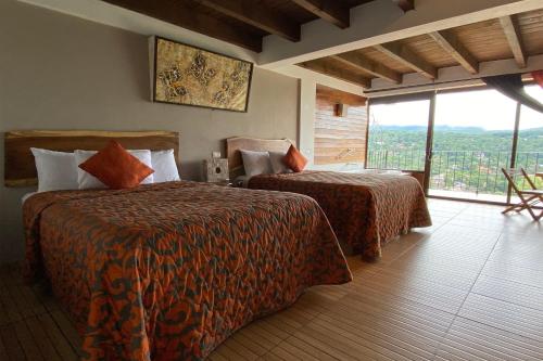 a hotel room with two beds and a large window at Hotel Santa Rosa in Valle de Bravo