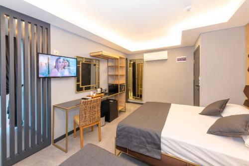 a hotel room with a bed and a desk and a tv at Fly And Stay Airport Hotel in Istanbul