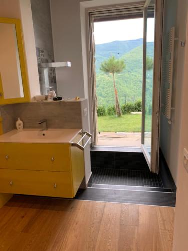 een badkamer met een wastafel en een groot raam bij CASA MONTE DI SOPRA jacuzzi & sauna in Fanano