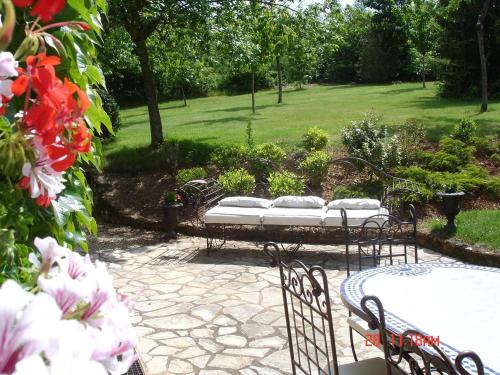 a patio with a table and chairs and flowers at La Grenouille in Saint-Adjutory