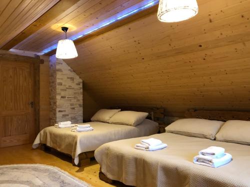 two beds in a room with wooden walls at Брусний View House in Sheshory