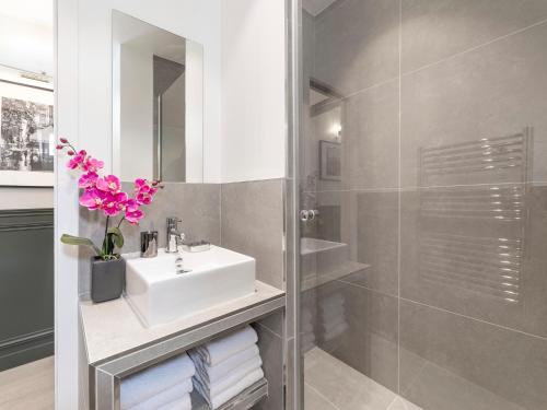 une salle de bain avec un lavabo blanc et une douche dans l'établissement LivinParis - Luxury 3 Bedrooms Opera II, à Paris