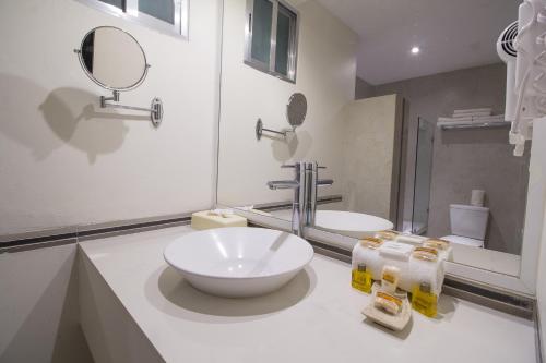 a white bathroom with a sink and a mirror at Hotel Tulija Palenque in Palenque