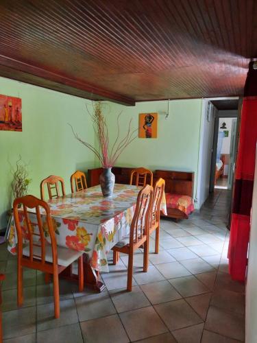 a dining room table with chairs and a vase on it at Le Jardin de Massieux in Bouillante