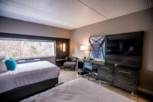 Habitación de hotel con cama, escritorio y TV. en Hotel Indigo Harrisburg – Hershey, en Harrisburg
