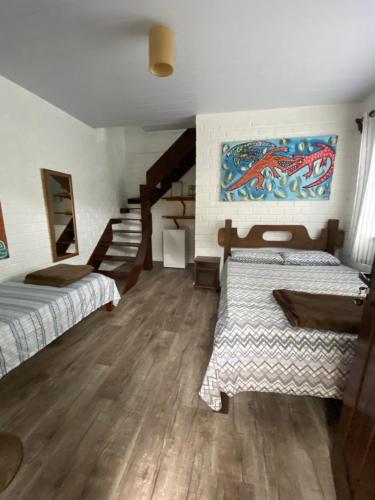 a room with two beds and a painting on the wall at Pousada Familia Quandt in Guarda do Embaú