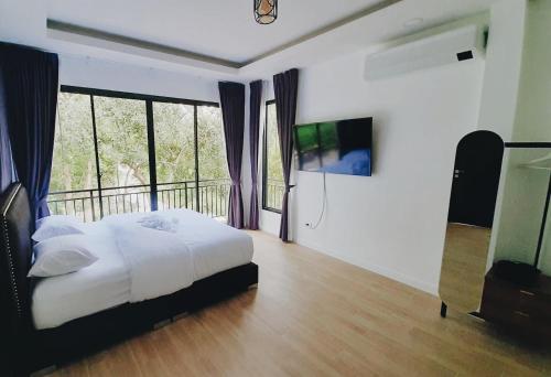 a bedroom with a bed and a balcony with windows at Parada Ayutthaya 