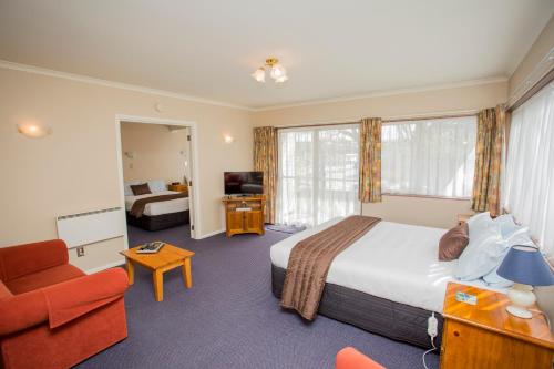 um quarto de hotel com uma cama, um sofá e uma cadeira em Parklands Motor Lodge Timaru em Timaru