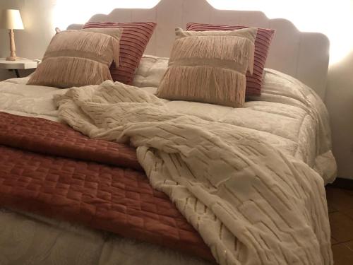a bed with red and white blankets and pillows at Il Bosco Guest House Subiaco in Subiaco