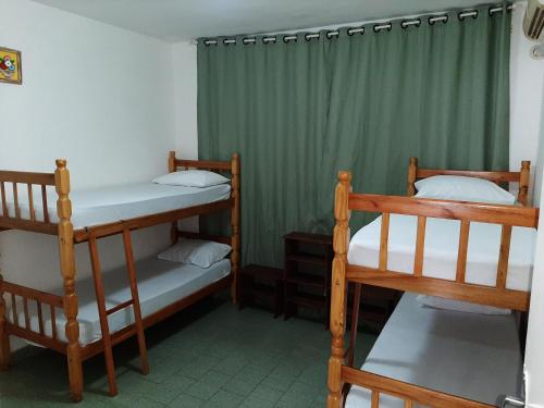 Ce dortoir comprend 2 lits superposés et des rideaux verts. dans l'établissement Pousada Pedra do Sol, à Parati