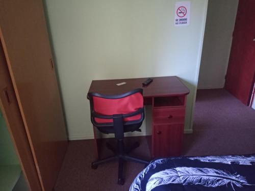 a desk with a red chair in front of a desk at Hostal El Toque de Pilar in Punta Arenas