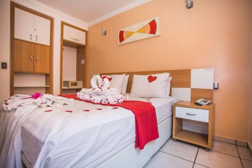 - une chambre avec un lit doté de draps blancs et d'une couverture rouge dans l'établissement diRoma Fiori com Roupa de Cama Parque Aquatico Academia e Garagem, à Caldas Novas