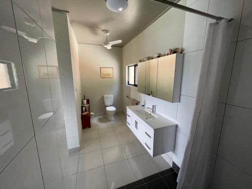 Baño blanco con lavabo y aseo en Riva-La-Vista-Cooktown, en Cooktown