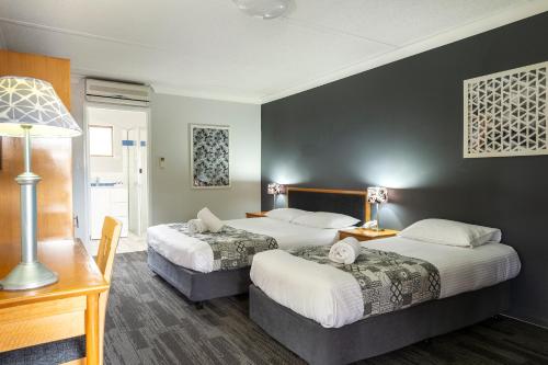 a hotel room with two beds and two lamps at Country Motel Ipswich in Ipswich